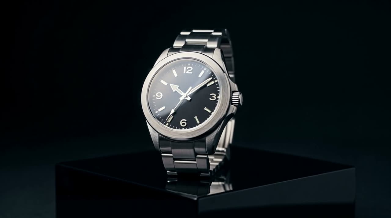 A steel wristwatch on a black pedestal